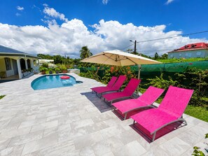 A swimming pool with lounge chairs and an umbrella. - Tropical Villa - Comfort and Relaxation (Petit-Bourg)