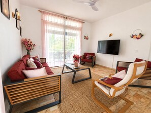 A living room with a sofa, chairs, a coffee table, a flat-screen TV, and a balcony with a view. - Tropical Villa - Comfort and Relaxation (Petit-Bourg)