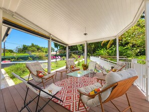 A covered outdoor seating area with cushioned chairs, a glass-top table, and a patterned rug. - Tropical Villa - Comfort and Relaxation (Petit-Bourg)