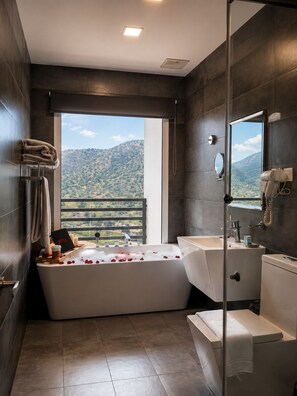 A modern bathroom with a large bathtub, a separate shower area, and a sink.