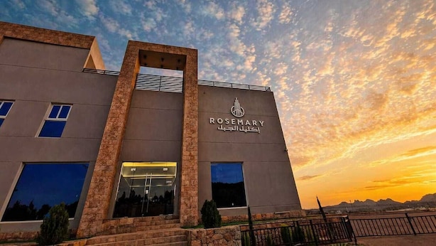 A modern building with a sign reading 'ROSEMARY' and Arabic script, featuring a stone facade and large windows. - ROSEMARY HOTEL  (Taif)