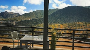 A balcony with a table and chairs, overlooking a mountainous landscape with a clear sky. - ROSEMARY HOTEL  (Taif)
