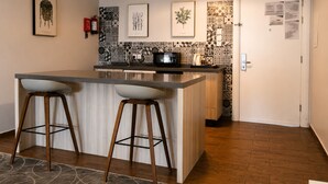 A kitchen with a central island, two bar stools, a microwave, and patterned backsplash. - ROSEMARY HOTEL  (Taif)