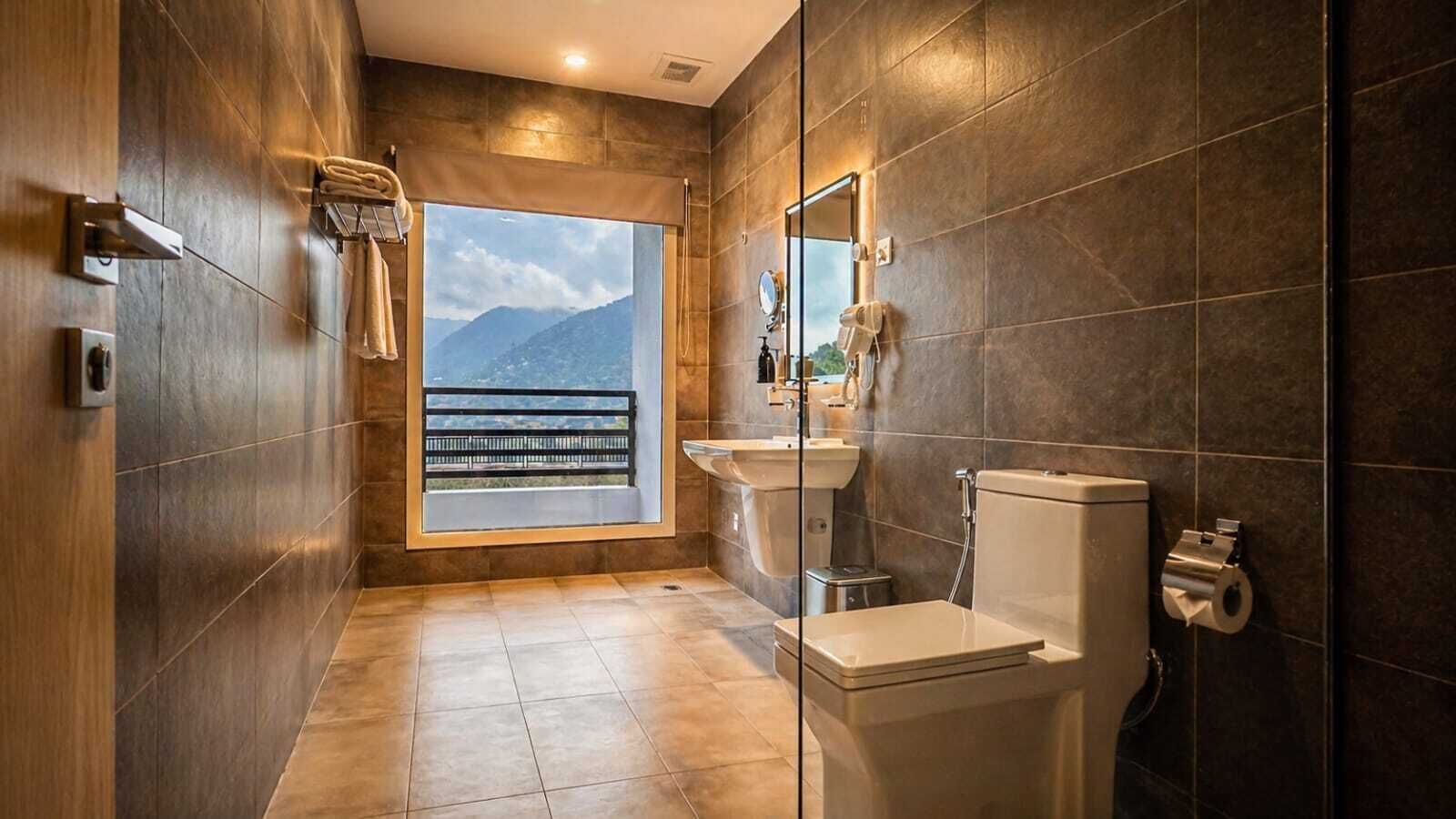 A modern bathroom with a toilet, sink, and shower. There is a window with a view of mountains.