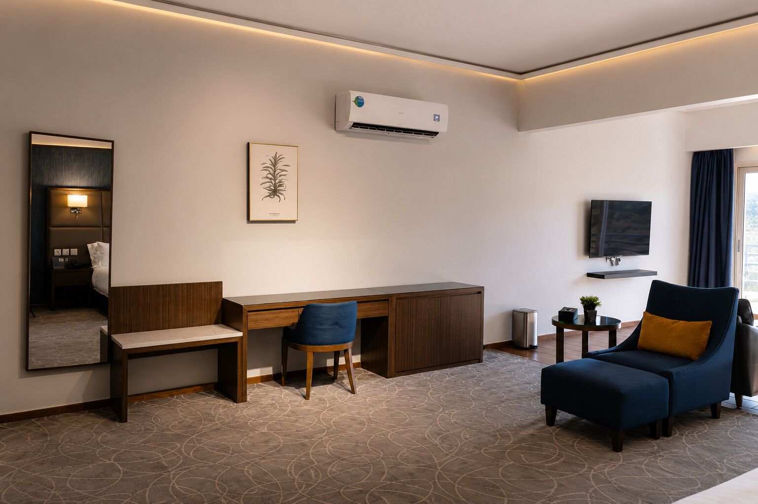 A hotel room with a desk, chair, sofa, TV, air conditioning unit, and a mirror.