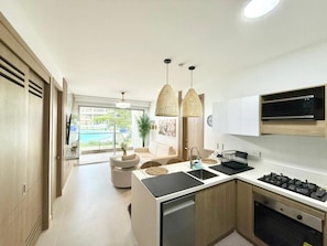 A modern kitchen with a central island, pendant lighting, and a view to a pool area. - Baia Kristal Prive 4 1A (Cartagena)