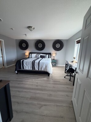 A bedroom with a bed, bedside tables, a desk, and a chair.