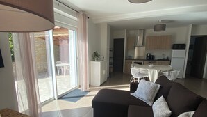 Una sala de estar moderna con un sofá, una mesa de comedor y una cocina al fondo.