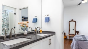 Un bagno moderno con doppio lavandino, un ampio specchio e una ventola a soffitto.