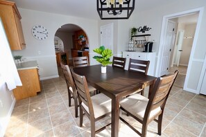 A dining area with a wooden table and chairs, a clock on the wall, and a coffee station. - Misty Meadows |Southern Lancaster Stay (Quarryville)