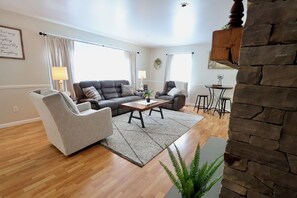 A living room with a sofa, armchair, coffee table, and a stone accent wall. - Misty Meadows |Southern Lancaster Stay (Quarryville)