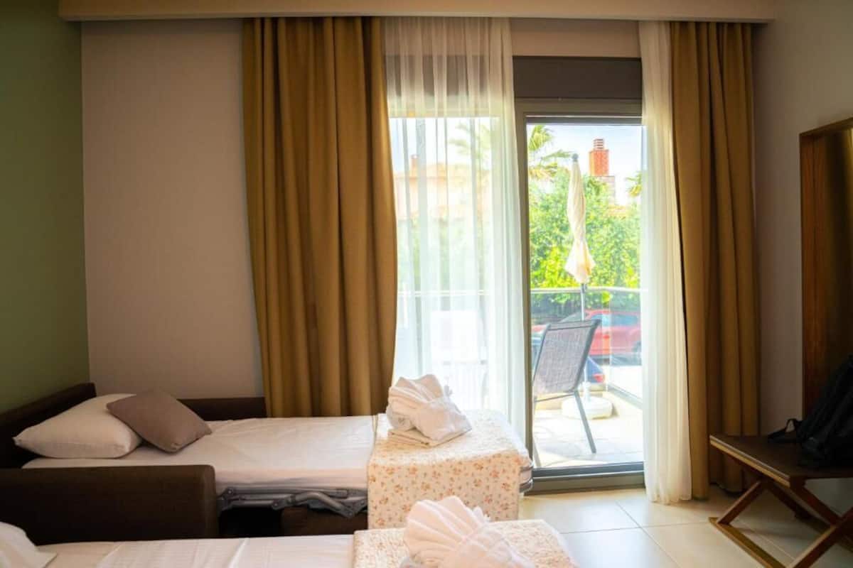 Une chambre d’hôtel avec deux lits, un balcon avec une chaise et une table avec des serviettes.