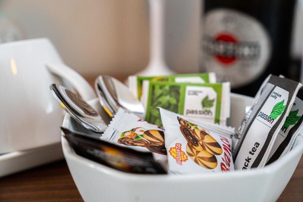 Una taza blanca llena de varios paquetes de té, incluyendo marcas como Passion y Té Negro, sobre una superficie de madera.