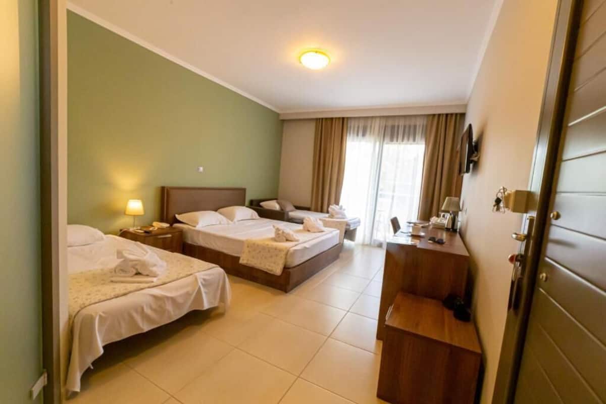 Une chambre d’hôtel avec deux lits, un bureau et un miroir.