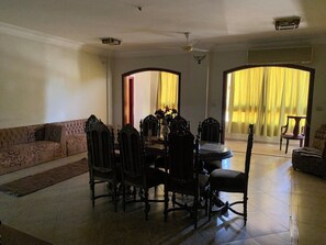 A dining area with a table and chairs, a sofa, and a view through a doorway.