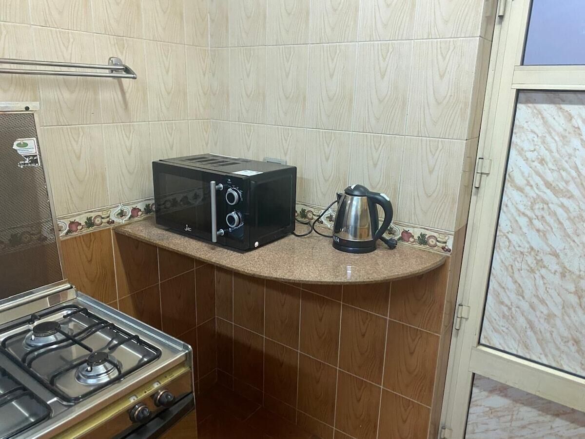Uma cozinha com fogão a gás, torradeira e chaleira sobre a bancada.