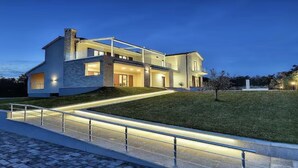 A modern two-story house with a well-lit exterior, a paved driveway, and a grassy lawn. - Luxury 5 Bed, 7 Bath, Villa. Pool, Gym, Sauna, Hottub, Parking, 2 terr w/Seaview (Jursici)