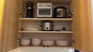 Un meuble de cuisine contenant une machine à café, une mijoteuse et plusieurs bols.