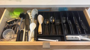 Un tiroir contenant divers ustensiles de cuisine, notamment des couteaux, des cuillères et une râpe.