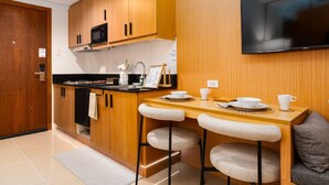 Una cocina moderna con armarios de madera, un microondas negro y una zona de comedor con dos taburetes tipo bar.