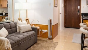 Una sala de estar moderna con un sofá, una lámpara y una cocina al fondo.