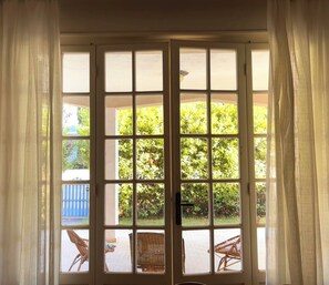 A room with a large glass door leading to an outdoor area with wicker furniture and greenery. - Cottage with large patio and bike path that connects directly to the waterfront (Cecina)
