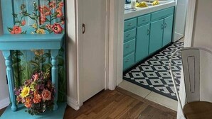 Een keuken met blauwgroene kastjes, een houten vloer en een stoel.