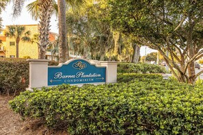 A sign for 'Bourbon Plantation Condominium' surrounded by lush greenery and palm trees. - Coastal Comfort 2 Queen Beds, pool, near beach! (St. Simons Island)
