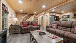 L'intérieur d'une cabane en rondins, avec un canapé, une table basse et un escalier.