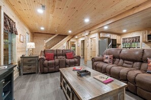 L'intérieur d'une cabane en rondins, avec un canapé, une table basse et un escalier.