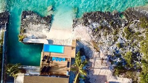 An aerial view of a resort with a swimming pool, lounge chairs, and a beach area. - Pool, Beach, kayaks, great snorkeling, calm side of the island,  (Exuma)