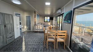A spacious room with a dining area, a sofa, a window with a view of the beach, and a ceiling with recessed lighting. - Pool, Beach, kayaks, great snorkeling, calm side of the island,  (Exuma)