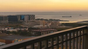 A coastal cityscape with modern buildings, a marina, and a clear view of the sea. - SkyLine CtyView Condotel BREEZE RESIDENCES near MOA,NAIA AIRPORT,PICC,US Embassy (Pasay City)