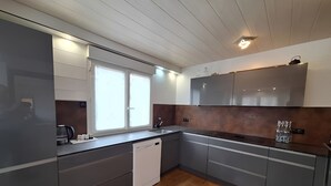 Una cocina moderna con armarios grises, lavavajillas y una ventana que proporciona luz natural.