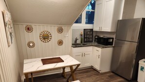 A compact kitchen with white cabinets, a stainless steel refrigerator, a marble countertop, and decorative wall mirrors. - Private 2BR Apartment w/ Private Entrance – Entire Upstairs Unit (Portsmouth)