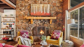 A cozy living room with a stone fireplace, wooden shelves, and comfortable seating. - Stylish & Cozy "Nut House" - Great & Game Room - Spa (Big Bear)