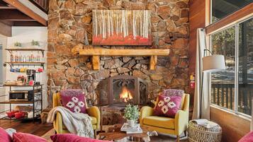 Una sala de estar acogedora con chimenea de piedra, estantes de madera y asientos cómodos.