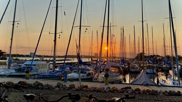 A marina with multiple sailboats docked at sunset. - Cozy apartment Strandallee in Burg/Fehmarn. (Burg/Fehmarn)