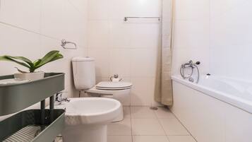 A modern bathroom with a toilet, bidet, and bathtub.