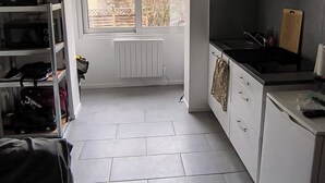 A compact kitchen with white cabinets, a black stove, and a window overlooking a residential area.