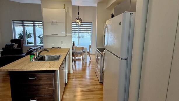Eine moderne Küche mit einer Holzarbeitsplatte, Edelstahlgeräten und Blick ins Freie durch große Fenster.