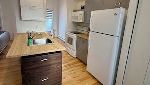 Eine moderne Küche mit Holzboden, einer integrierten Spüle, einer Mikrowelle, einem Herd und einem Kühlschrank.