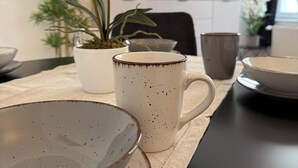 Una mesa con platos, una taza y una orquídea en maceta.