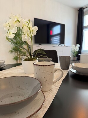 Una mesa con platos, una taza y una orquídea en maceta.