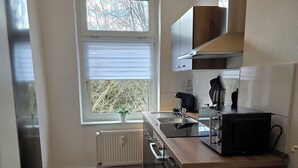 Una cocina moderna con ventana, armarios de madera, horno empotrado y encimera con tetera.