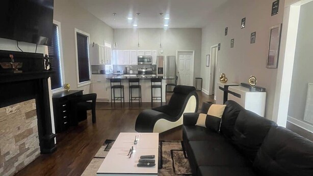 Una sala de estar moderna con un sofá negro, una mesa de centro y una chimenea.