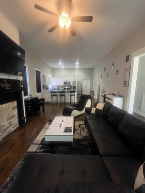 A modern living room with a black sofa, a coffee table, and a fireplace.