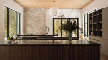 A modern kitchen with a stone wall, a large window, and a wooden ceiling.