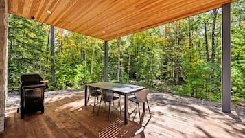 Private covered forest patio with outdoor dining and BBQ grill