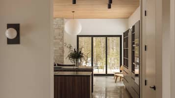 Modern designer kitchen with floor-to-ceiling windows and serene forest views
